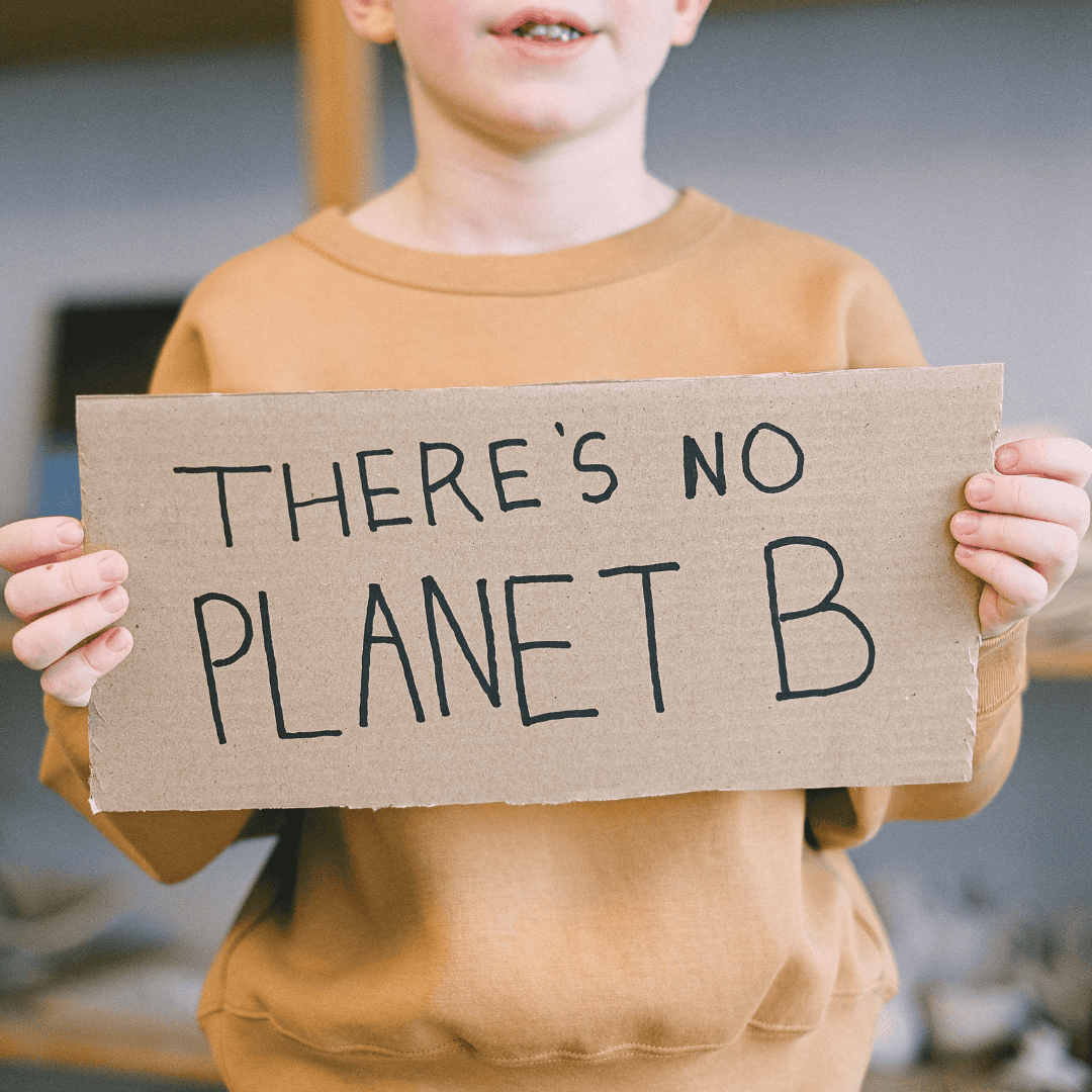 young boy holding a carboard sign There's No Planet B